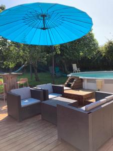 HeugasにあるGîte 10 personnes dans la Nature proche Océan Landesのプールサイドのデッキに座る青い傘