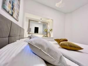a white bedroom with a large bed with pillows at Rab Downtown Place in Rab