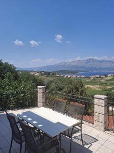 Una mesa y sillas en un patio con vista al agua. en VILLA Apartments Mate Cebalo, en Lumbarda