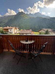 a table and two chairs on a balcony with mountains at Garni Appartements Des Alpes in Solda