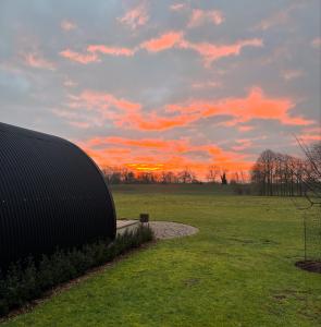 Una puesta de sol en un campo con un edificio en el césped. en The Goose In The Woods, en Wellesbourne