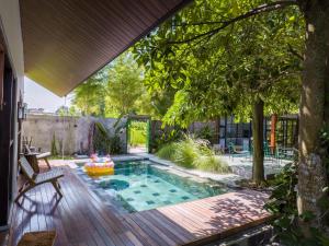 a swimming pool in a yard with a wooden deck at Karuna Villa Prambanan in Yogyakarta