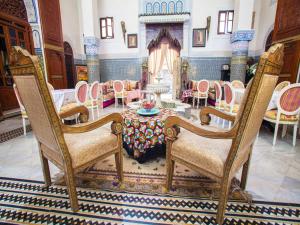 een eetkamer met stoelen en een tafel en een open haard bij Palais Al Firdaous in Fès