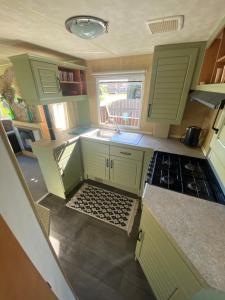 a small kitchen with green cabinets and a sink at Grzybowo in Ryn