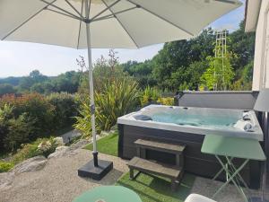 a hot tub with an umbrella and a bench at Le Coucher de Soleil Spa in Bessens