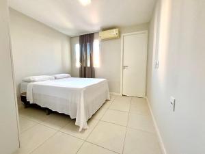 ein weißes Schlafzimmer mit einem Bett und einem Fenster in der Unterkunft Golf Ville Residence Resort, apartamento 3 suítes, 110m2, Porto das Dunas próx ao Beach Park in Aquiraz + 31 Fotos