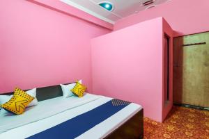 a pink room with a bed with colorful pillows at Hotel O by OYO Rajdhani Hotel in Kākori