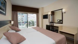 トレモリノスにあるSandos Griegoのベッド、デスク、窓が備わるホテルルームです。
