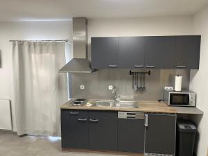 a kitchen with black cabinets and a sink and a microwave at Jaroldsmühle in Jarolden
