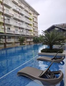 a swimming pool with two lounge chairs in front of a building at Luxury Budget one Bedroom with living room and Kitchen Rest and fly at Amani Grand Resort in Pusok