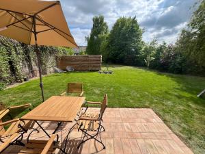 a wooden table and chairs with an umbrella in a yard at Helle Loft mit eingenem Garten in Templin