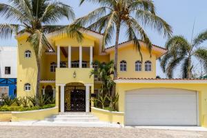 a yellow house with palm trees in front of it at Cheerful 4 Bedroom house with Swimming Pool in Mezcales