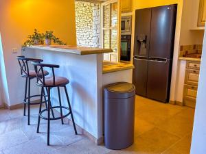 ゴルドにあるVilla de vacances à Gordes avec piscine partagée, La Bastide de Léaのキッチン(スツールと冷蔵庫付きのバー付)