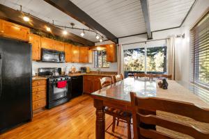 eine Küche mit einem Tisch und einem schwarzen Kühlschrank in der Unterkunft Entire Cabin, Walk to Ski Slopes, Hot Tub, Pet Friendly, Fast WiFi, 2 Parking, 2 Fireplace, Wash & Dryer, Fenced, Fire Pit, BBQ, Hike, Golf, Zoo in Big Bear Lake