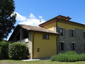 une maison jaune avec un toit dans l'établissement La Rocca -- Monticello Apartments, à Medesano