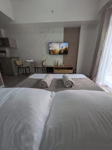 a bedroom with two white beds and a flat screen tv at Cebu Airport budget Luxury living Rest& Fly at Amani Grand Resort in Pusok