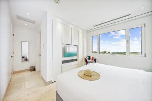 a white bedroom with a large bed with a hat on it at 2 BR Oceanview Condo Coral Shell 3e in Oranjestad +81 photos