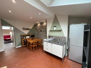 eine Küche mit einem weißen Kühlschrank und einem Tisch in der Unterkunft Nid Douillet Sous Les Toits - Calme et Cosy in Saint-Étienne