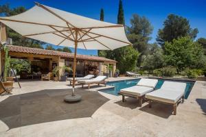 a large white umbrella sitting next to a swimming pool at Villa Des oliviers in Le Beausset