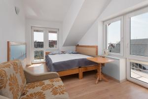 a bedroom with a bed and a table and windows at pensjonat Alka in Jastarnia