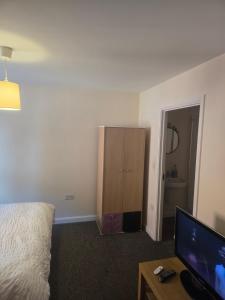a bedroom with a bed and a dresser and a television at Ensuite room in Wolverhampton city center in Wolverhampton