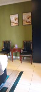 two chairs and a table in a room with green walls at Lot 3127, Modipane in Gaborone