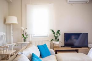 a living room with a white couch and a tv at Endless Seaview Villa in Argostoli
