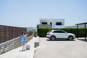 a woman standing next to a car with a suitcase at Prasonisi Villas in Kattavía