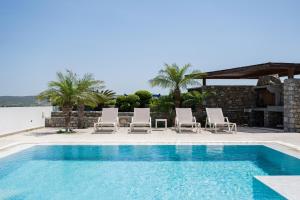 a swimming pool with chaise lounge chairs and a swimming pool at Prasonisi Villas in Kattavía
