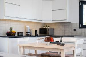 a kitchen with a wooden table and white cabinets at Prasonisi Villas in Kattavía