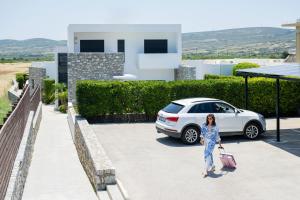 a woman standing in front of a white car at Prasonisi Villas in Kattavía