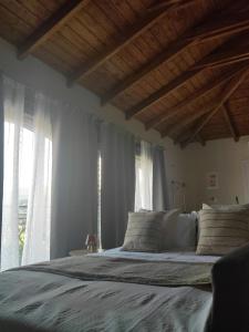 a bedroom with a large bed with white sheets and windows at Ανέμη in Panayía