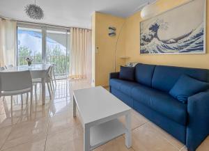 Una sala de estar con un sofá azul y una mesa. en T2, Calme & lumineux, au bout du jardin, la plage!, en La Grande-Motte