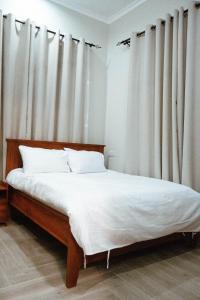een slaapkamer met een bed met witte lakens en gordijnen bij Roseney Home in Dar es Salaam