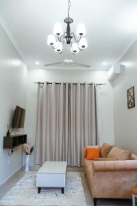 een woonkamer met een bank en een kroonluchter bij Roseney Home in Dar es Salaam