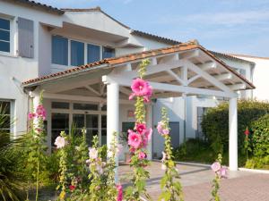 a pergola in front of a house with pink flowers at Thalacap Île de Ré - Thalasso & Spa in Ars-en-Ré