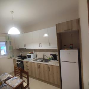 a kitchen with white cabinets and a white refrigerator at Ioli's apartment in Igoumenitsa +10 photos