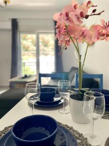 a table with plates and glasses and a vase with flowers at Marias Apartment in Pefkohori