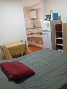 a kitchen with a bed and a white refrigerator at Sierras Altas Alojamientos in Villa Carlos Paz