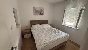 a small bedroom with a bed and a window at Apartmani Mirela in Krk
