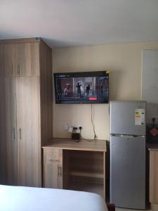 Habitación con nevera y TV en la pared. en Stylish Studio Apartments, StadeView Apartment, en Nairobi