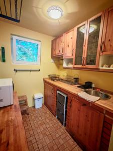 a kitchen with wooden cabinets and a sink and a window at TóPart Vendégház Velence in Velence
