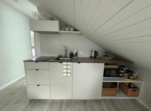 a kitchen with white cabinets in an attic at Marių kampelis in Juodkrantė +20 photos