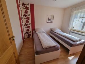 two beds in a small room with a window at Ferienwohnung MiA in Frankenau