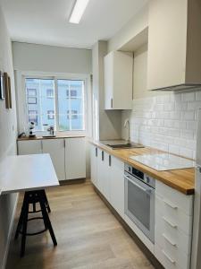 a kitchen with white cabinets and a table and a window at Apartamento Mar de Cruz in Pontevedra +13 photos