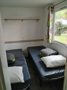 Dos camas en una habitación pequeña con ventana. en Camping rivages des Landes, en Aureilhan