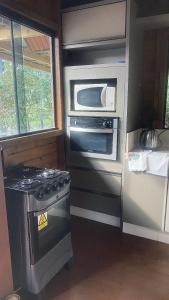a kitchen with a stove and a microwave at Pousada Vale das Pedras in Pedras Grandes +20 photos