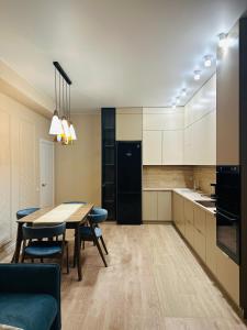 a kitchen with a table and chairs and a black refrigerator at Luxury 2- Bedroom with Balcony in Prime Location in Chişinău