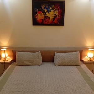 ein Bett mit zwei Kissen in einem Zimmer mit zwei Lampen in der Unterkunft Organic Stay in Greater Noida