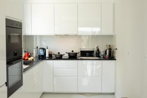 a white kitchen with white cabinets and appliances at Villa Julieta in Ferreiros de Avões